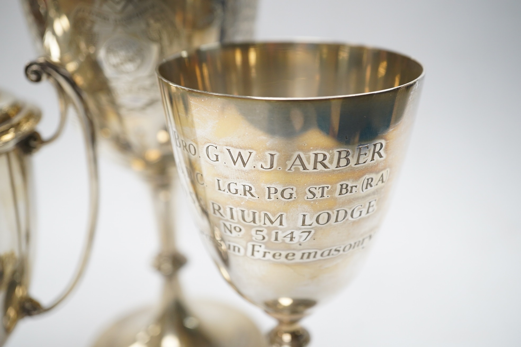 A Victorian engraved silver presentation goblet, with Masonic inscription, London, 1880, 19.5cm, together with a modern silver presentation goblet and a silver two handled presentation trophy cup and cover, 20.2oz. Condi